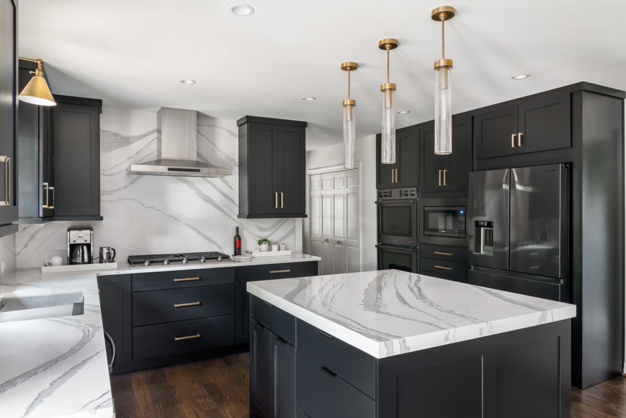 Modern Kitchen design with black cabinets, marble countertop and backsplash and pendent light over island