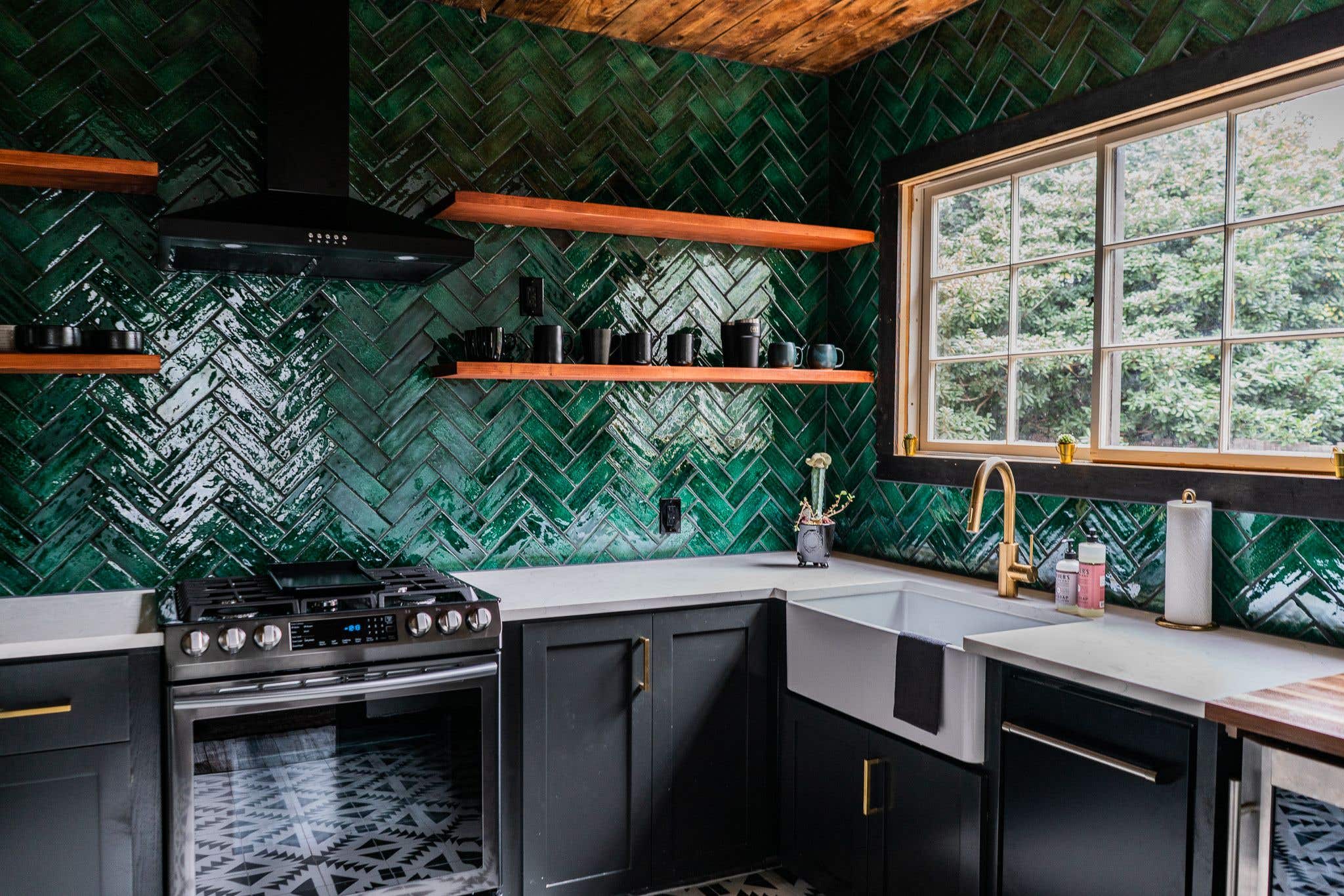 Green walls with black kitchen cabinets paired with open shelving, farmhouse sink and gold hardware