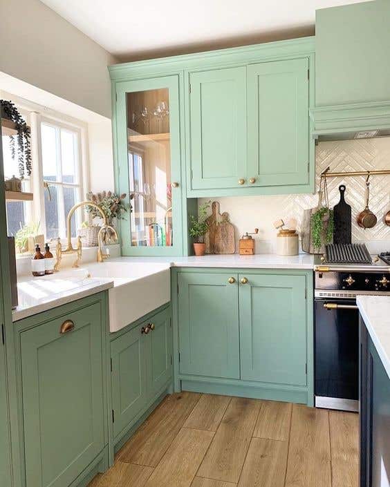 Mint colored kitchen cabinets paired with white countertops, farmhouse sink, gold hardware