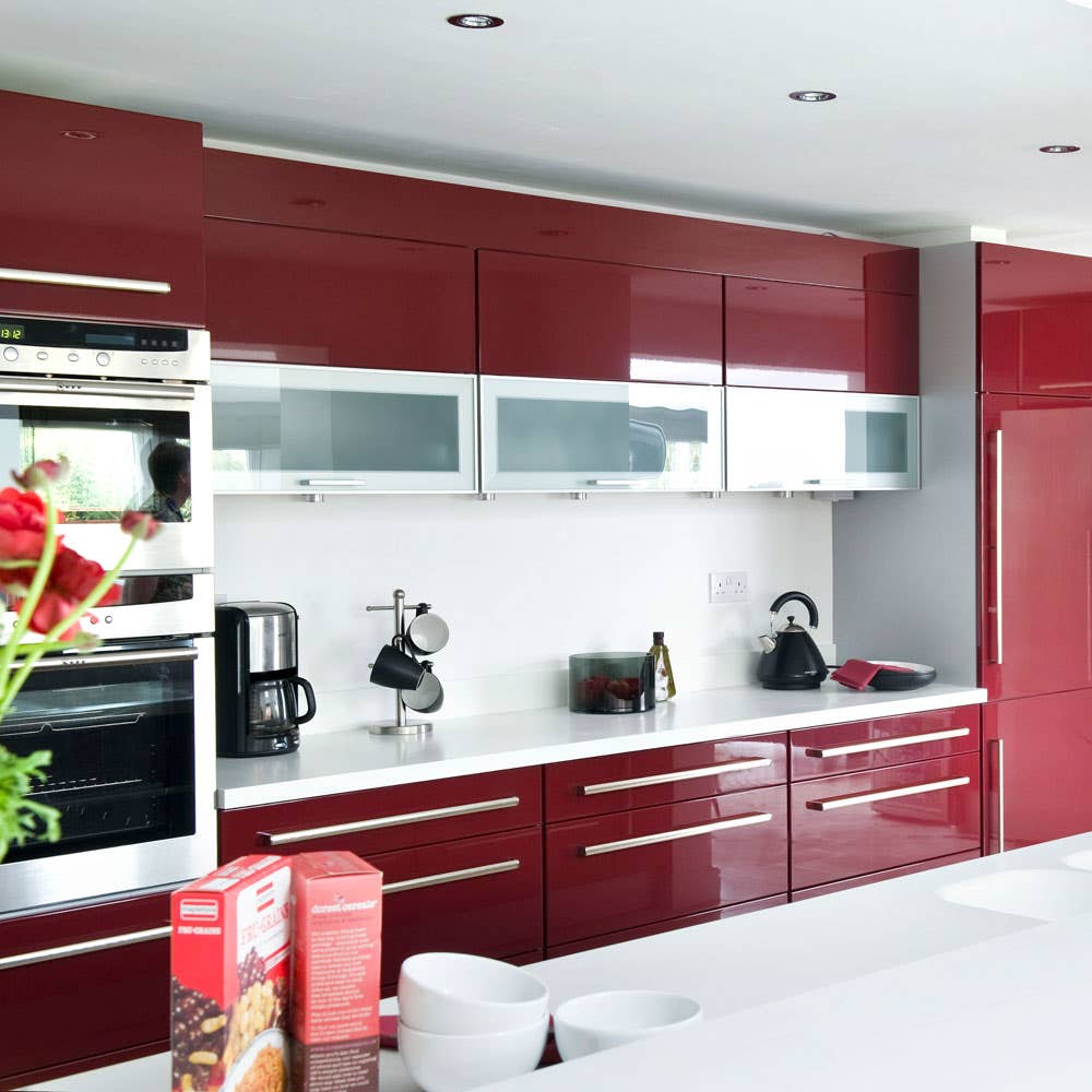 Kitchen design features Red kitchen cabinets with silver hardware and stainless steel appliances 