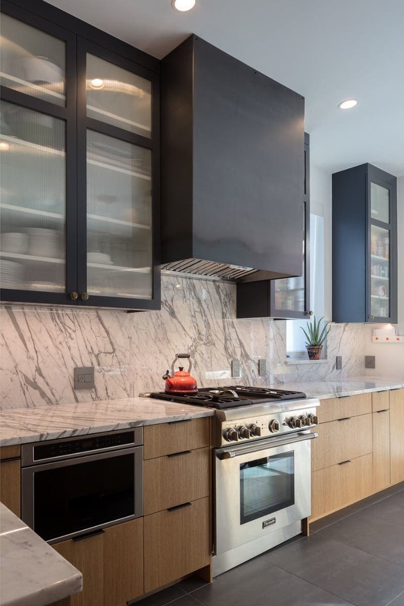 Kitchen design with black hood and real wood cabinets and marble countertop