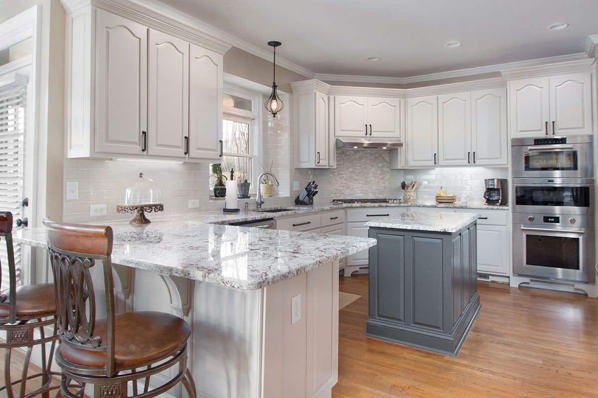 Cathedral kitchen cabinet doors paired with marble countertop, gray island, and Stainless Steel Appliances 