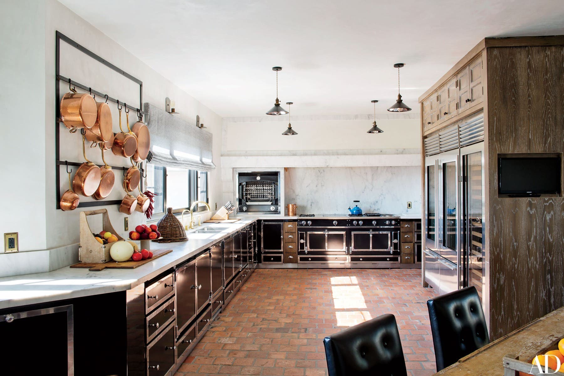 large kitchen space features an accent wall and Hanging pots and pans 