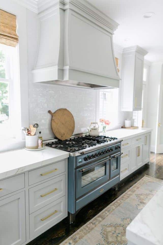 Kitchen design with large hood vent, white cabinets with gold hardware and SPC flooring 