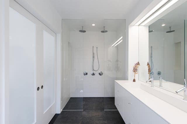 modern white bathroom with glass shower doors and dark tile floor