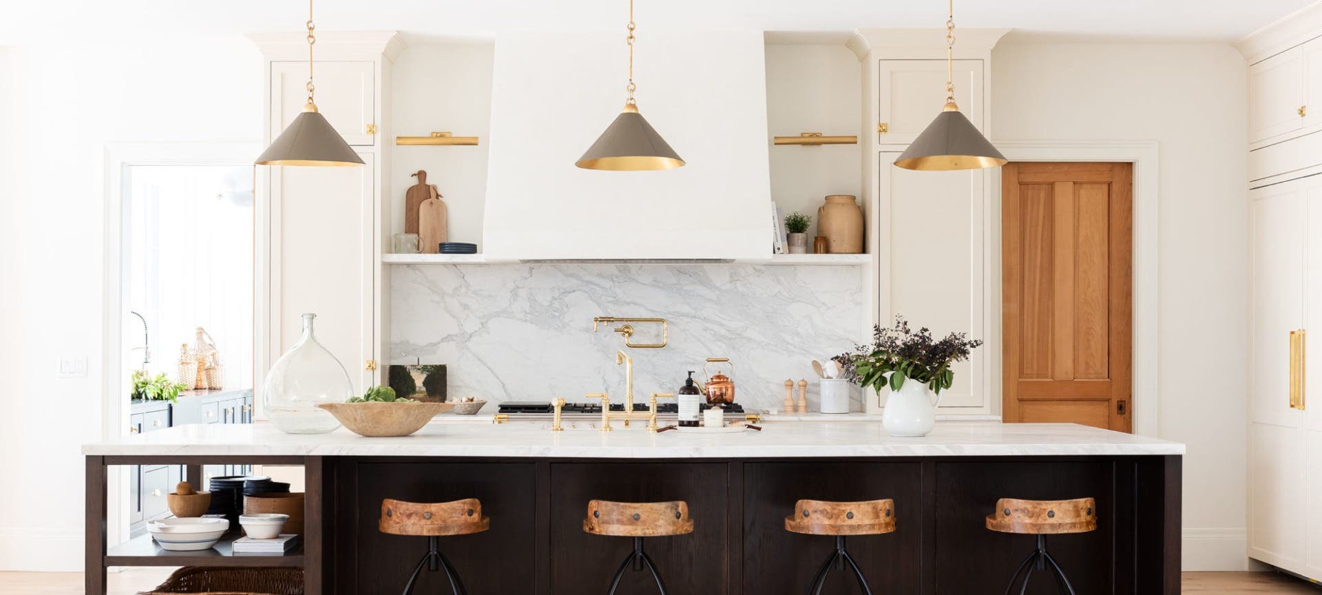 Modern kitchen design features cream colored cabinets, quartz countertops and stunning gold accents,