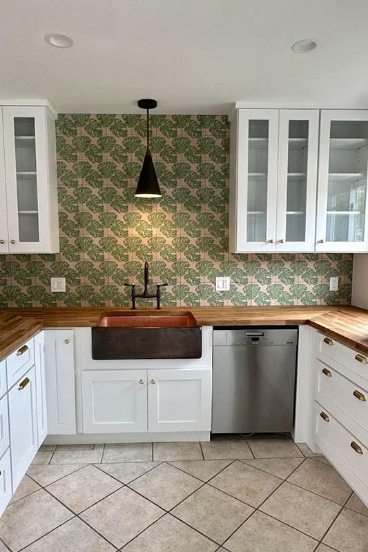 U shape kitchen with white cabinets, bronze hardware, wooden countertop and floral prints wallpaper