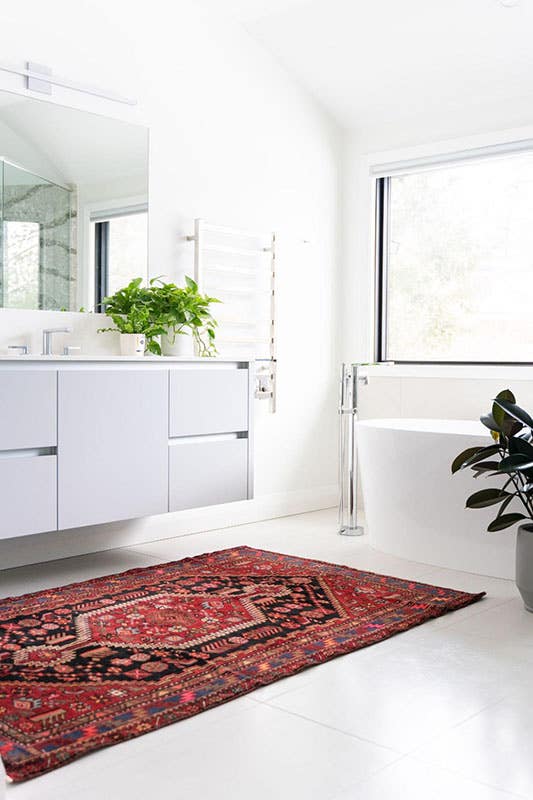 white themed bathroom with Jacuzzi, cabinets, mirror, marble floor, red color rug 