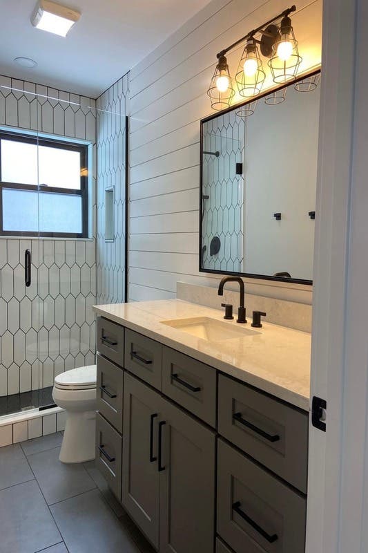 Gray bathroom vanity paired with matt black hardware and Bar lights