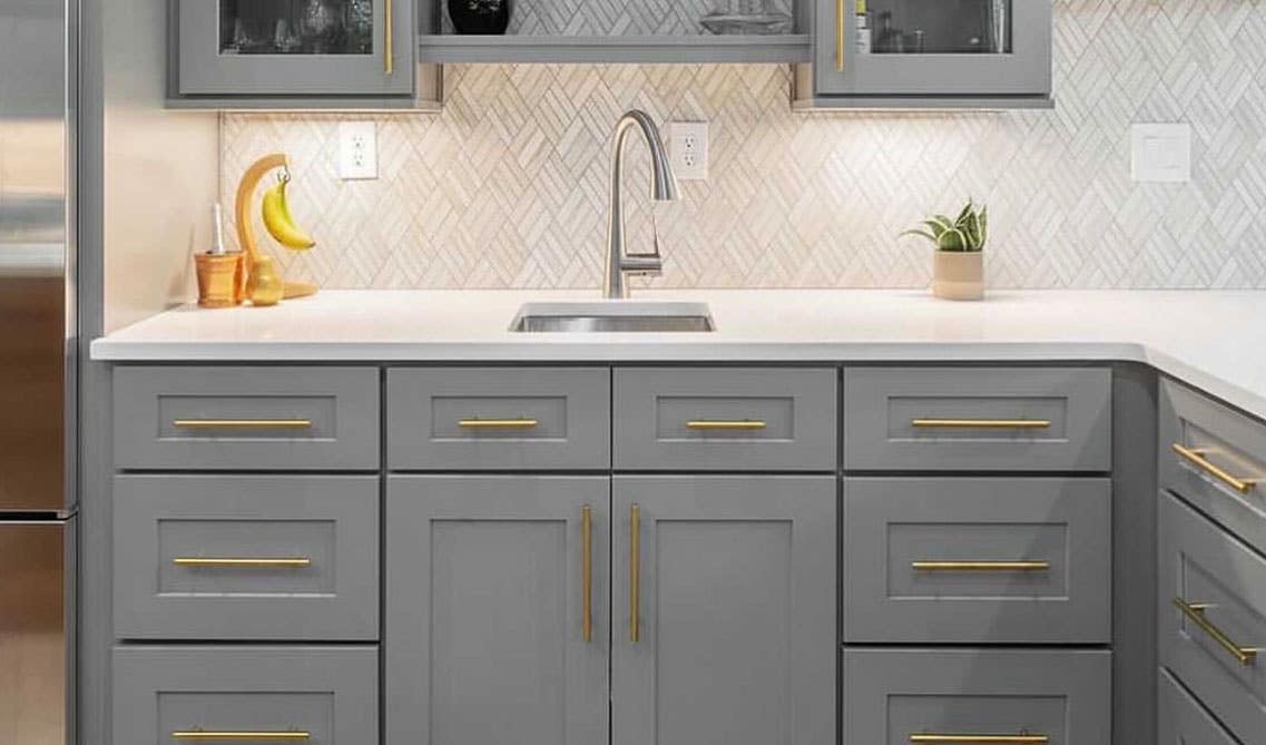 Grey Shaker Elite base cabinets with gold pulls, white countertop, and Vertical Running Bond subway tiles