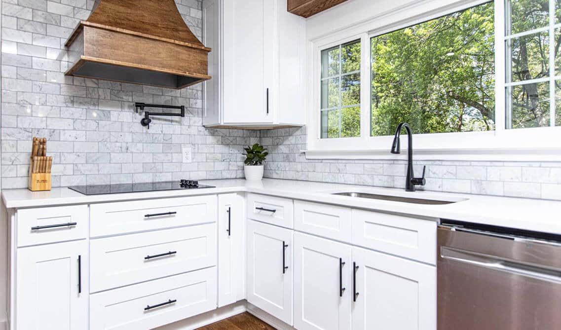 white cabinets and black hardware, white countertop, and wood hood