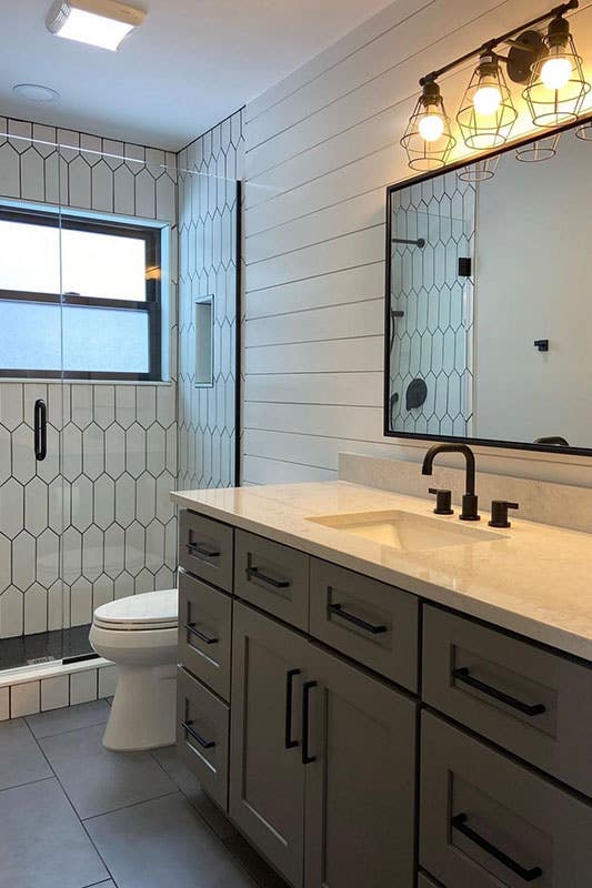 modern bathroom with gray vanity with marble countertops, square mirror and fixture lights