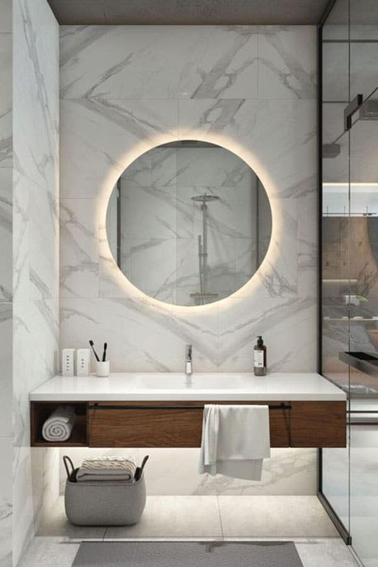 modern guest bath with floating vanity with lighting and large circular mirror with LED back lighting