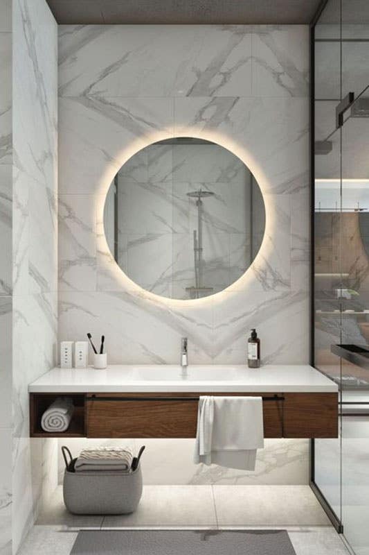 modern guest bath with floating vanity, vanity lighting and large circular mirror with LED back lighting modern guest bath with floating vanity with lighting and large circular mirror with LED back lighting