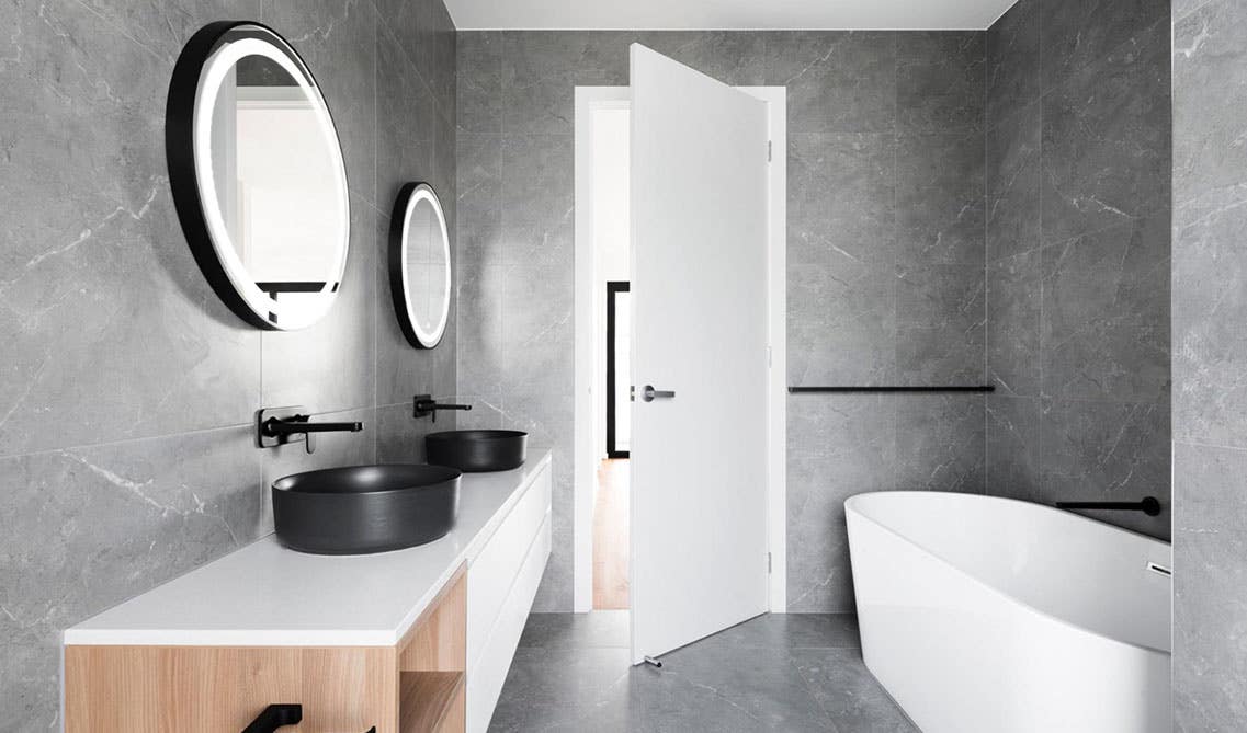 Modern bathroom with white vanity, black fixture, double sink with mirror, and bathtub 