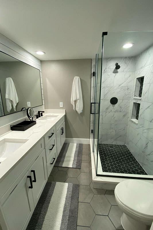 wall mounted white bathroom vanity with black fixture and separate shower area