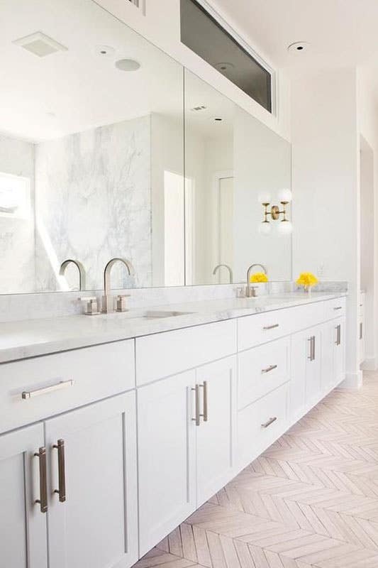 large white modern bathroom with white shaker cabinets, chrome hardware, double wide wall mirrors and double sink