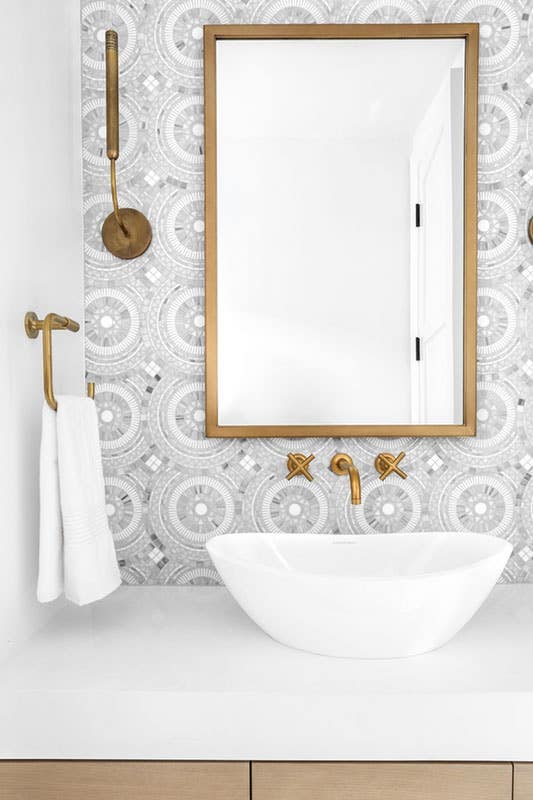 white ceramic vessel sink with large mirror, brass hardware and creative patterned wallpaper