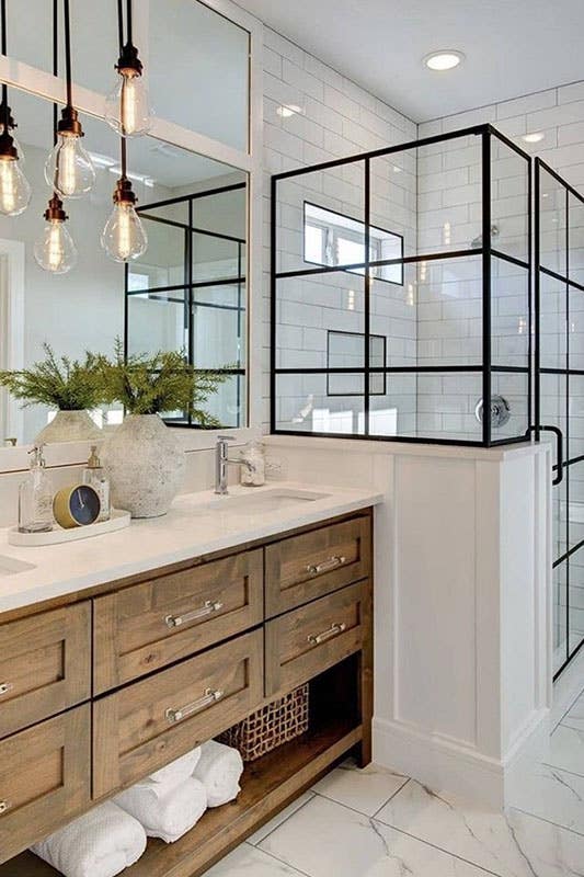 Natural wood shaker cabinets with white countertop and black framed shower door