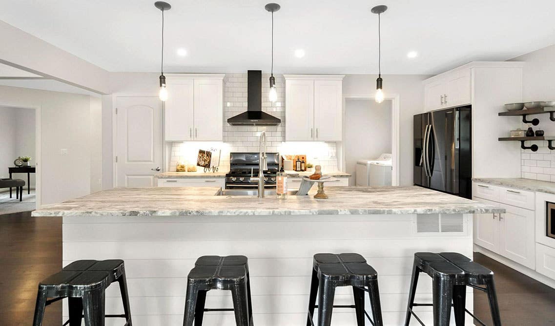 Kitchen with white cabinets, black appliances, and large island