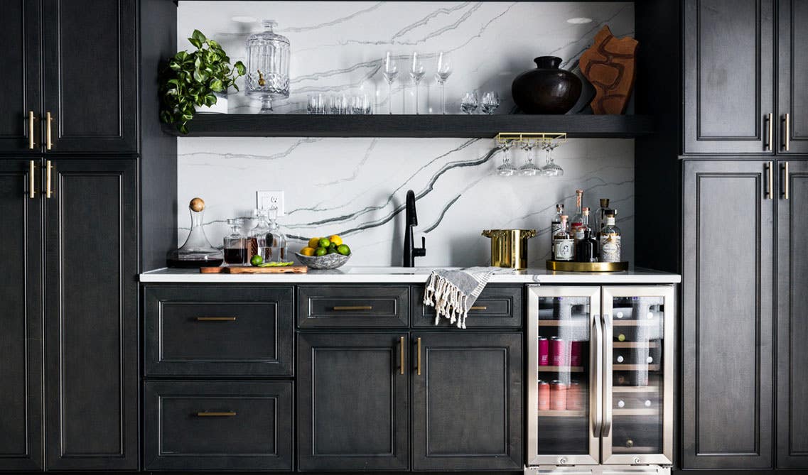 Black cabinets paired with gold pulls, Marble backsplash and white countertop