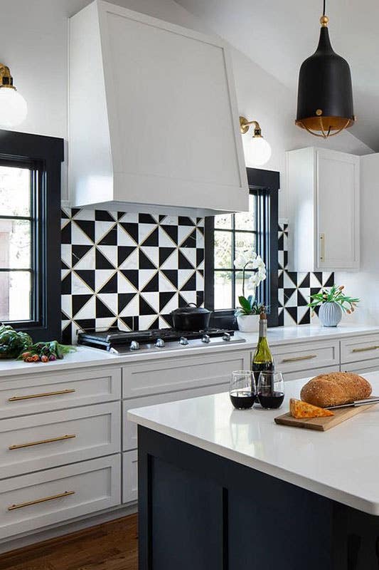 Kitchen with white cabinets, gold decorative hardware, white countertop and black and white pattern backsplash