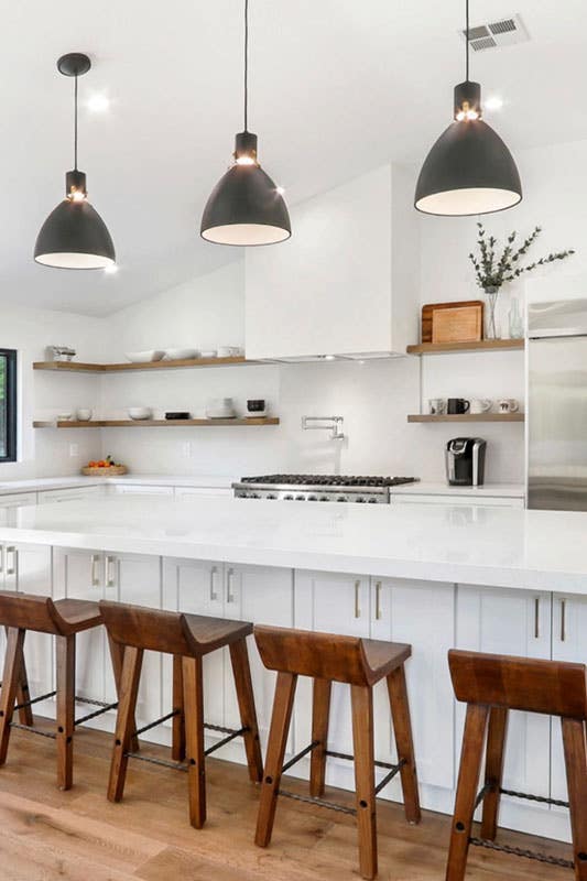 Kitchen with white cabinets, large island, floating shelves and personalized pendant light