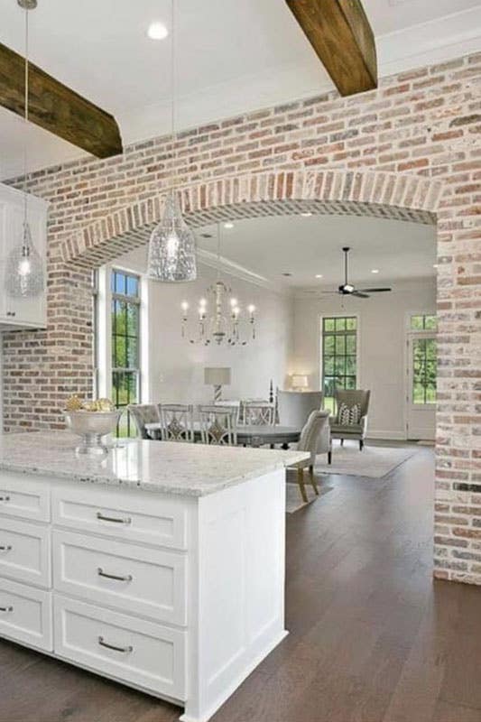 Red Brick Backsplash with white shaker cabinets countertop and spc flooring