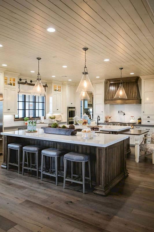 Modern farmhouse kitchen with large wood island, pendant lighting, marble countertops, wood floors and shiplap ceiling