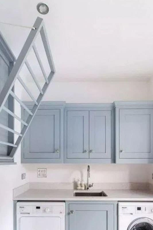 Small laundry room with blue cabinets, washer and dryer and undermount sink