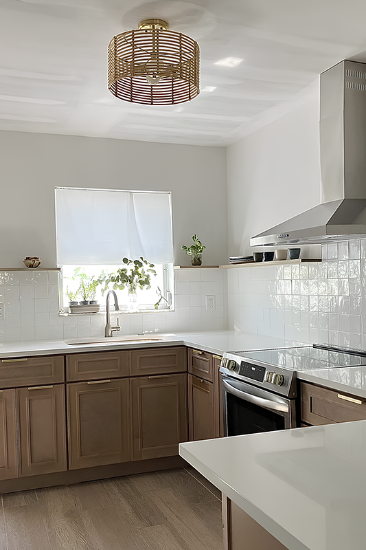 Brown kitchen cabinets paired with white countertop, subway tile backsplash and stainless steel appliances 