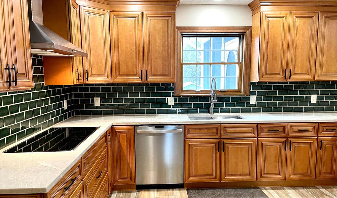 brown cabinets paired with green subway tiles and marble countertop 