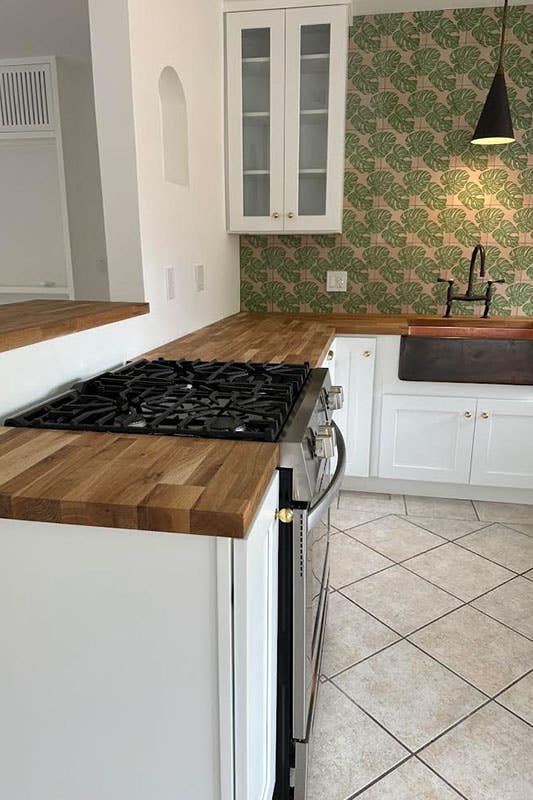 Kitchen with white cabinets, Butcher Block Countertop and floral print wallpaper