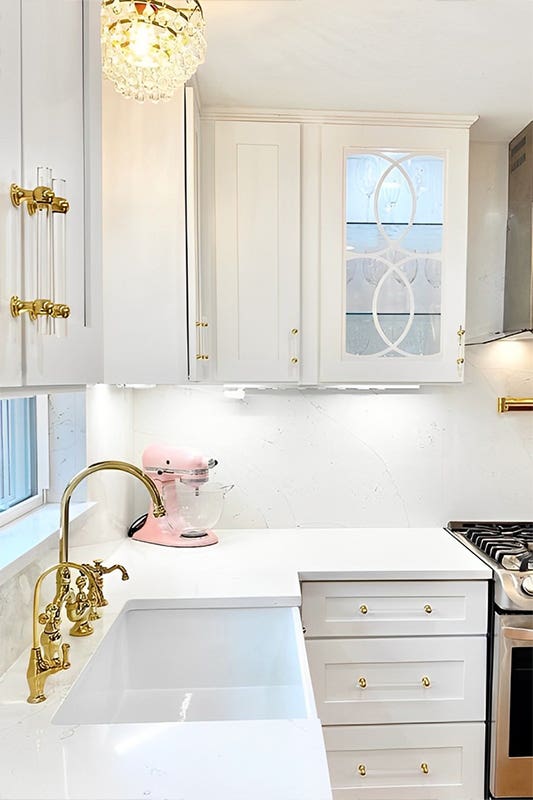 White cabinets with glass door, gold hardware, and steel appliances 
