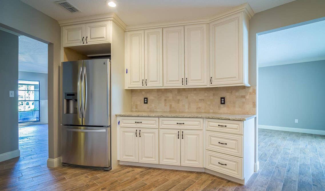 off white kitchen cabinets with Crown Molding to the Ceiling, stainless steel fridge and SPC flooring