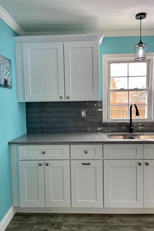 Single wall kitchen with shaker white cabinets with black countertop