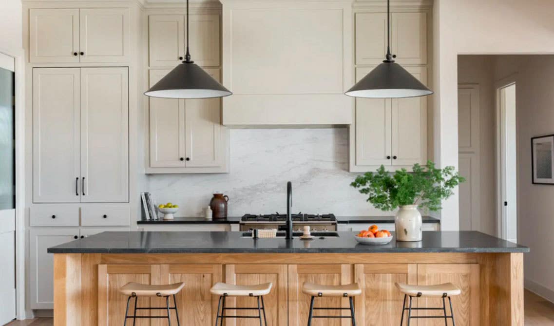 Cream cabinets kitchen with wood island and dark countertop, pendent lights, stool chairs