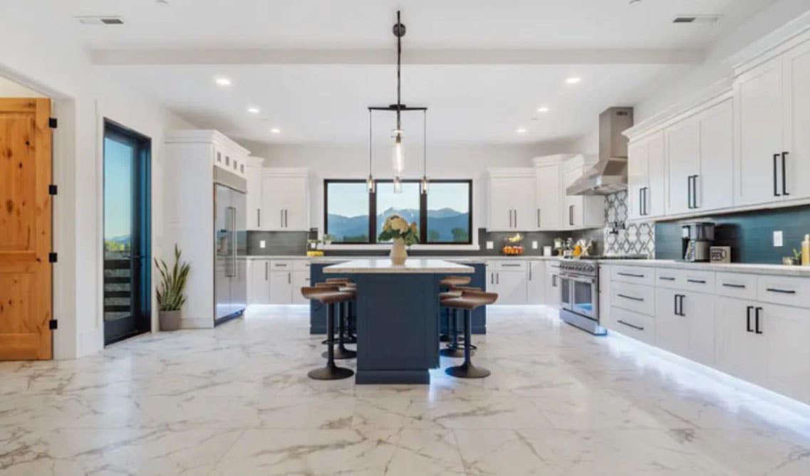 Large kitchen design with white cabinets and navy blue cabinet island, black matt puls and stylish lights