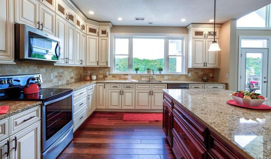 Traditional kitchen design with cream cabinets, granite countertops, stainless steel appliances and large window above sink