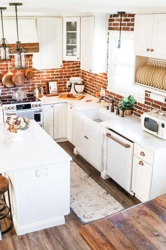 Rustic kitchen with white cabinets and bronze cabinet hardware, brick tile backsplash, small island