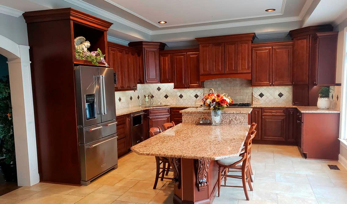 Cherry kitchen 10 foot ceiling cabinets and larger island with marble countertop, wooden chairs and tile floor