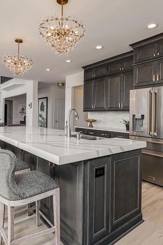 Kitchen with black cabinets, functional island and Classic Chandeliers