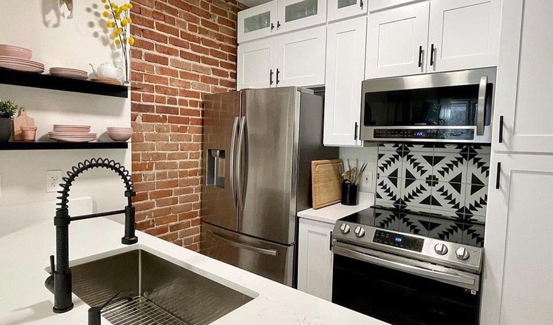 Classic Red Brick Backsplash with marble Countertop and bright white cabinets