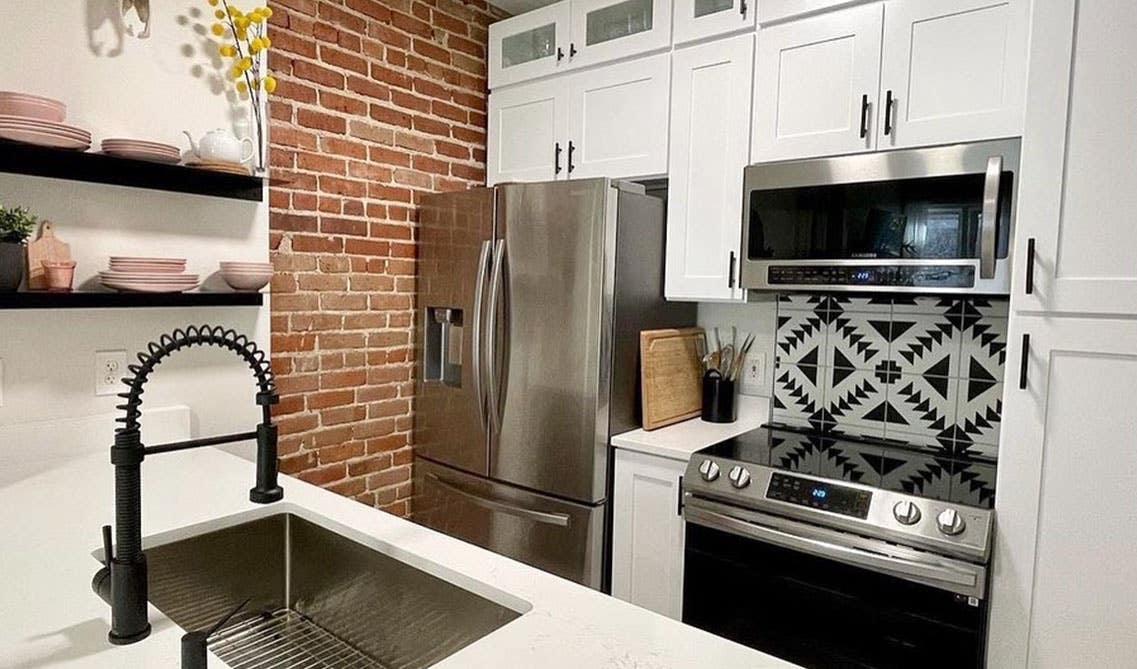 Classic Red Brick Backsplash with marble Countertop and bright white cabinets