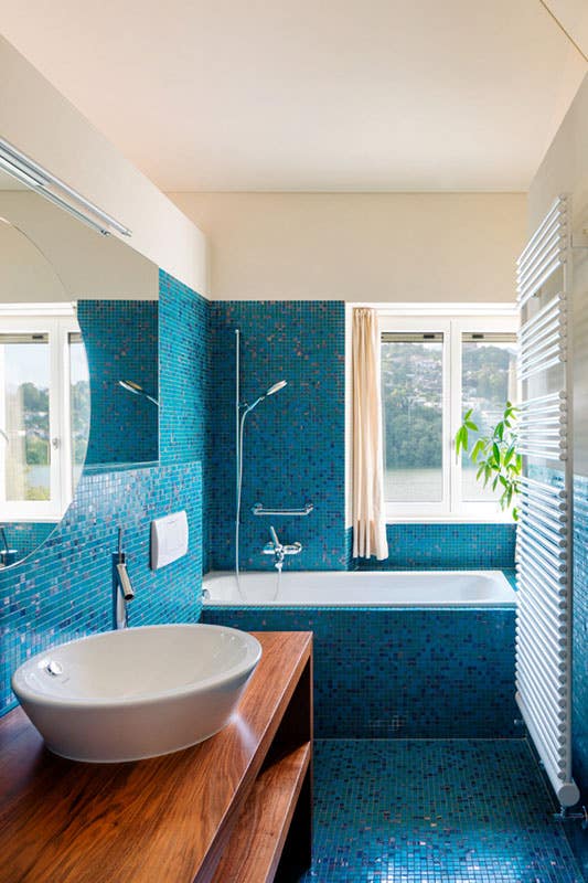 Coastal bathroom design with wood countertops, ceramic sink, stainless steel hardware and bathtub beside window 