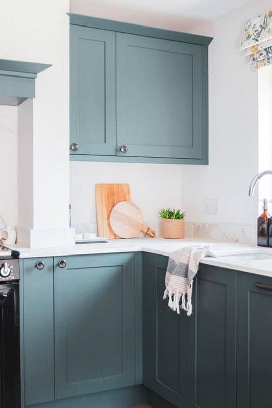 Kitchen design with teal cabinets and marble countertop