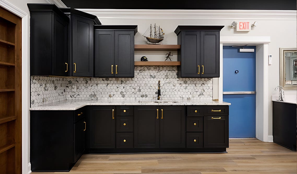 Craftsman Black Shaker cabinets paired with gold pulls, marble countertop and wooden shelves 