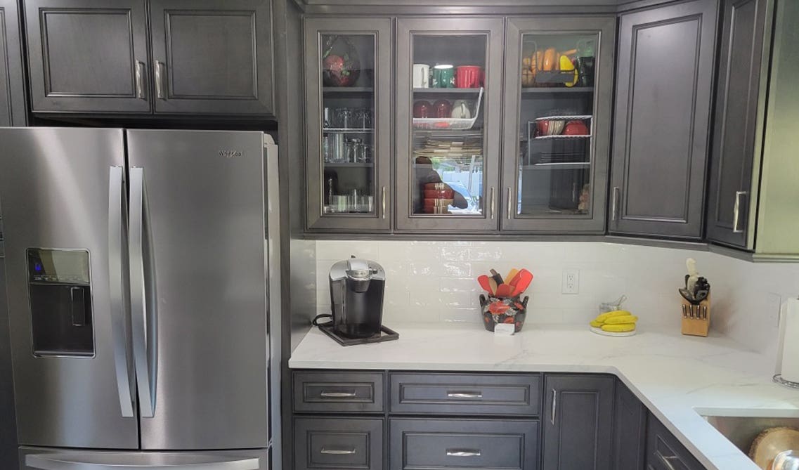 Grey kitchen cabinet with white countertop and subway tile backsplash 