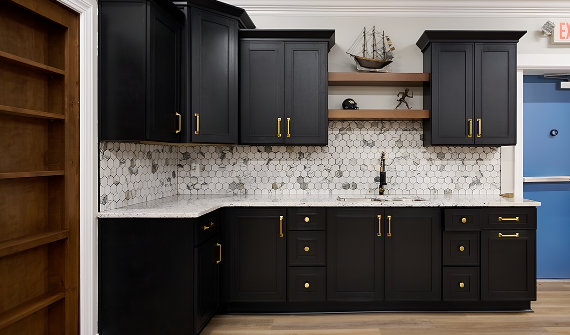 Black kitchen cabinets paired with gold hardware, tile backsplash and quartz countertop