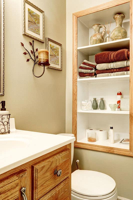 Beautiful Bathroom design features wood vanity with white countertop and Cut out Shelves for storage, antique wall decor